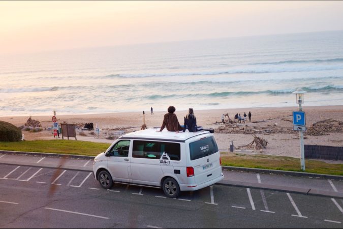 Couple sitting on top of a VAN-IT campervan during a road trip in France