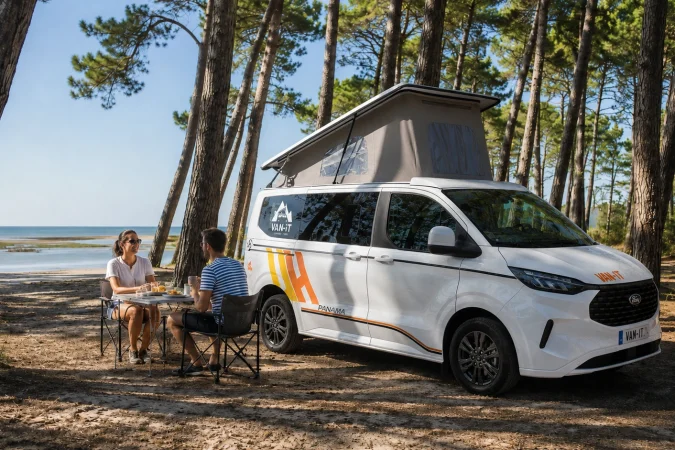 Couple devant un van VAN-IT en forêt côtière lors d’un road trip depuis Bordeaux