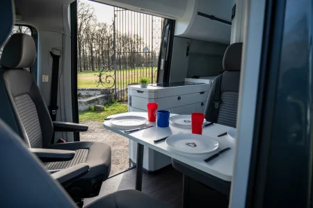 Coin repas avec table et sièges pivotants dans le Volkswagen Grand California.