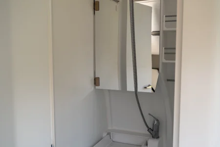 Salle d’eau du Volkswagen Grand California avec lavabo, douchette et miroir.