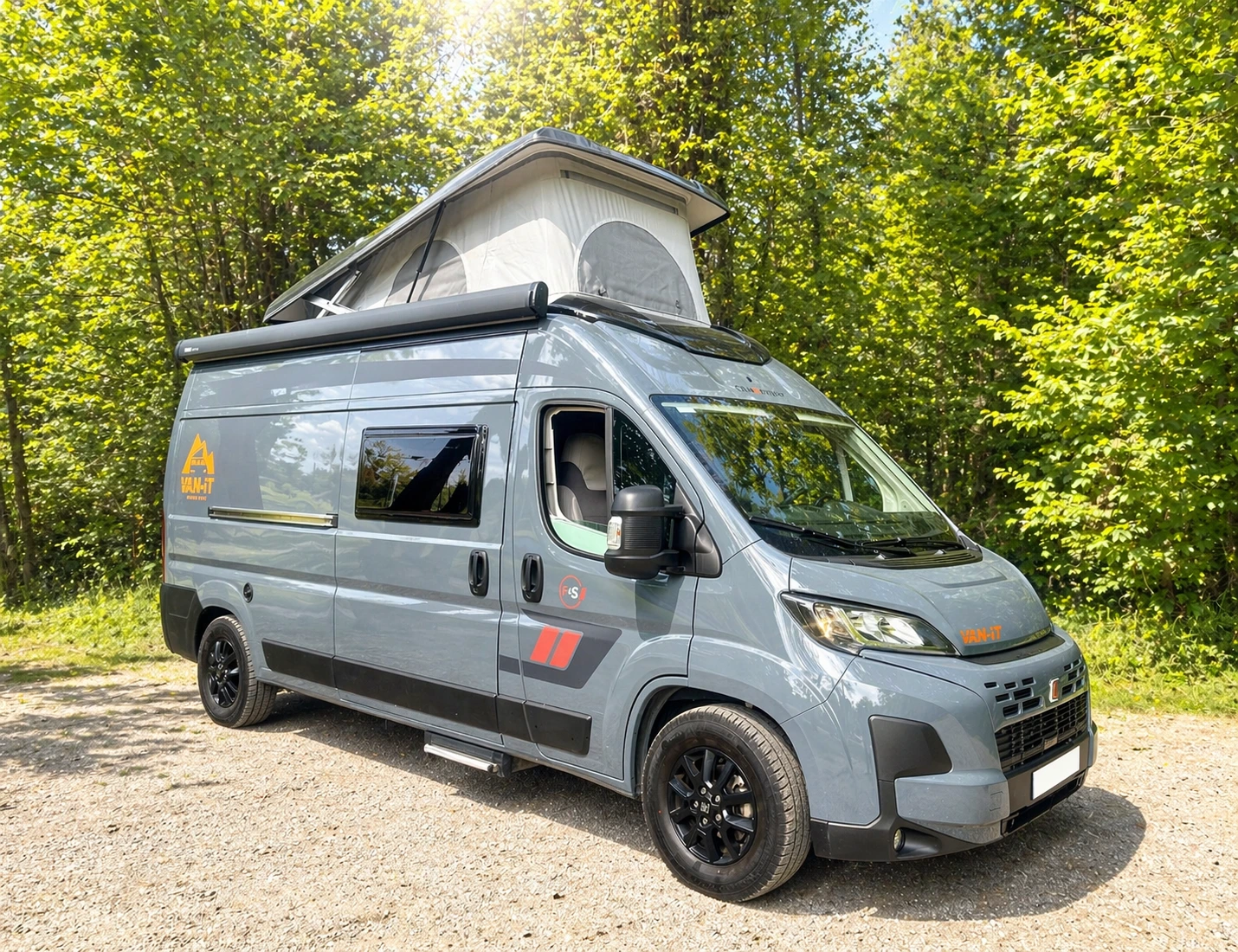 Fourgon aménagé Family+ avec toit relevable stationné en pleine nature.