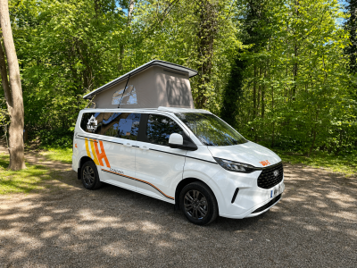 Van aménagé Ford Panama avec toit relevable stationné dans un environnement naturel.